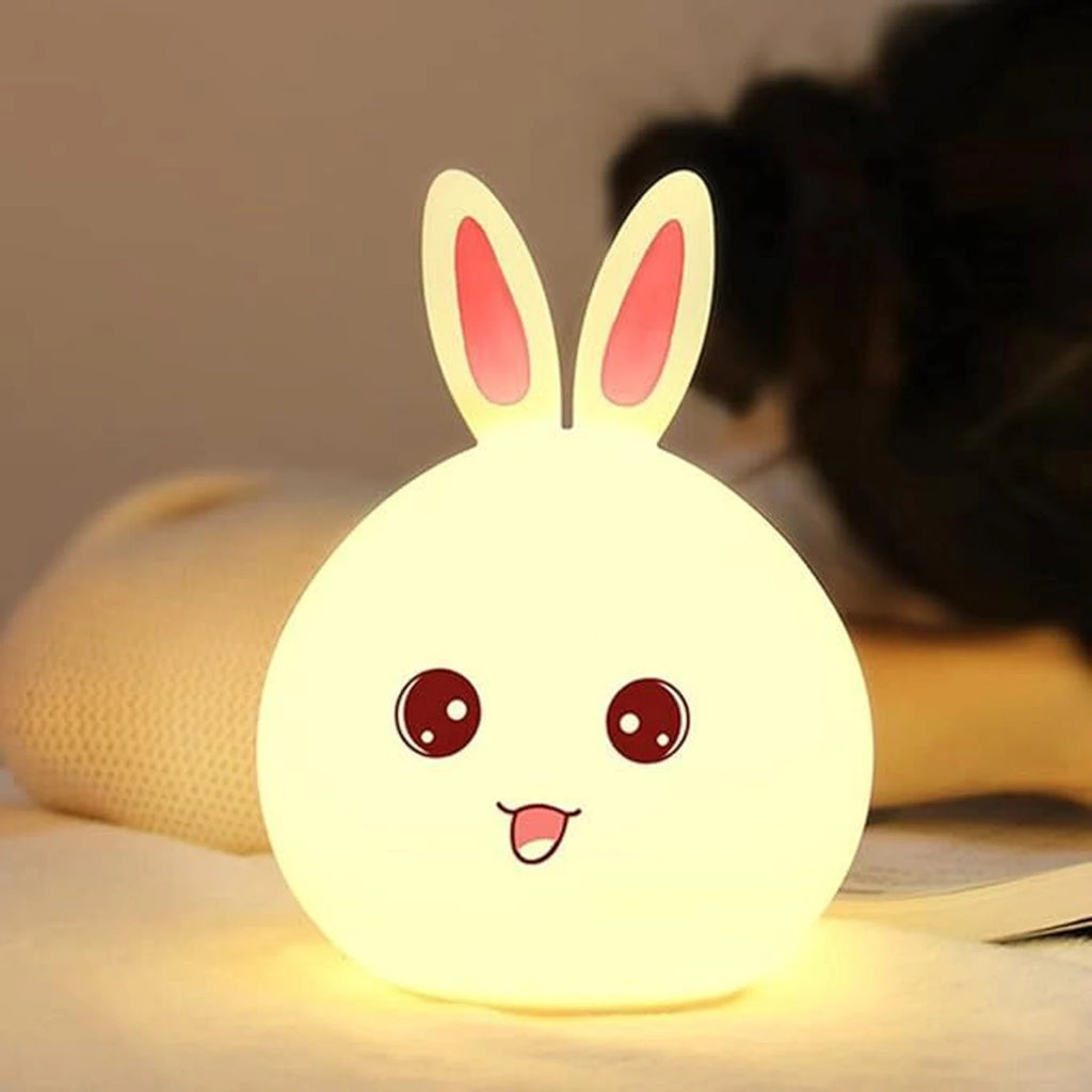 Cute Bunny Silicone Night Light glowing warm white on bedside table with child sleeping in background