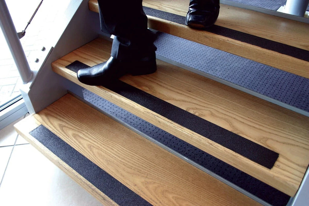 Anti-Slip Safety Tape on wooden stairs - person walking safely with black grip tape strips